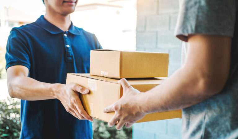 Delivery concept Asian Man hand accepting a delivery boxes from professional deliveryman at home