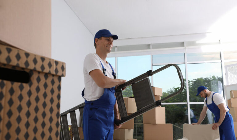 Moving service employees with ladder and cardboard boxes in room